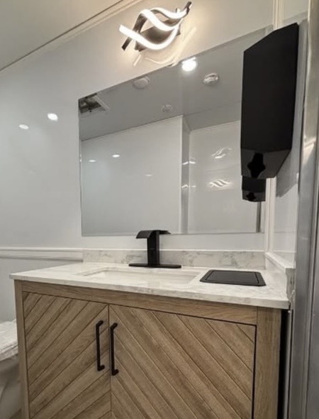 Marble interior with wood vanity, brushed fixtures and mirror